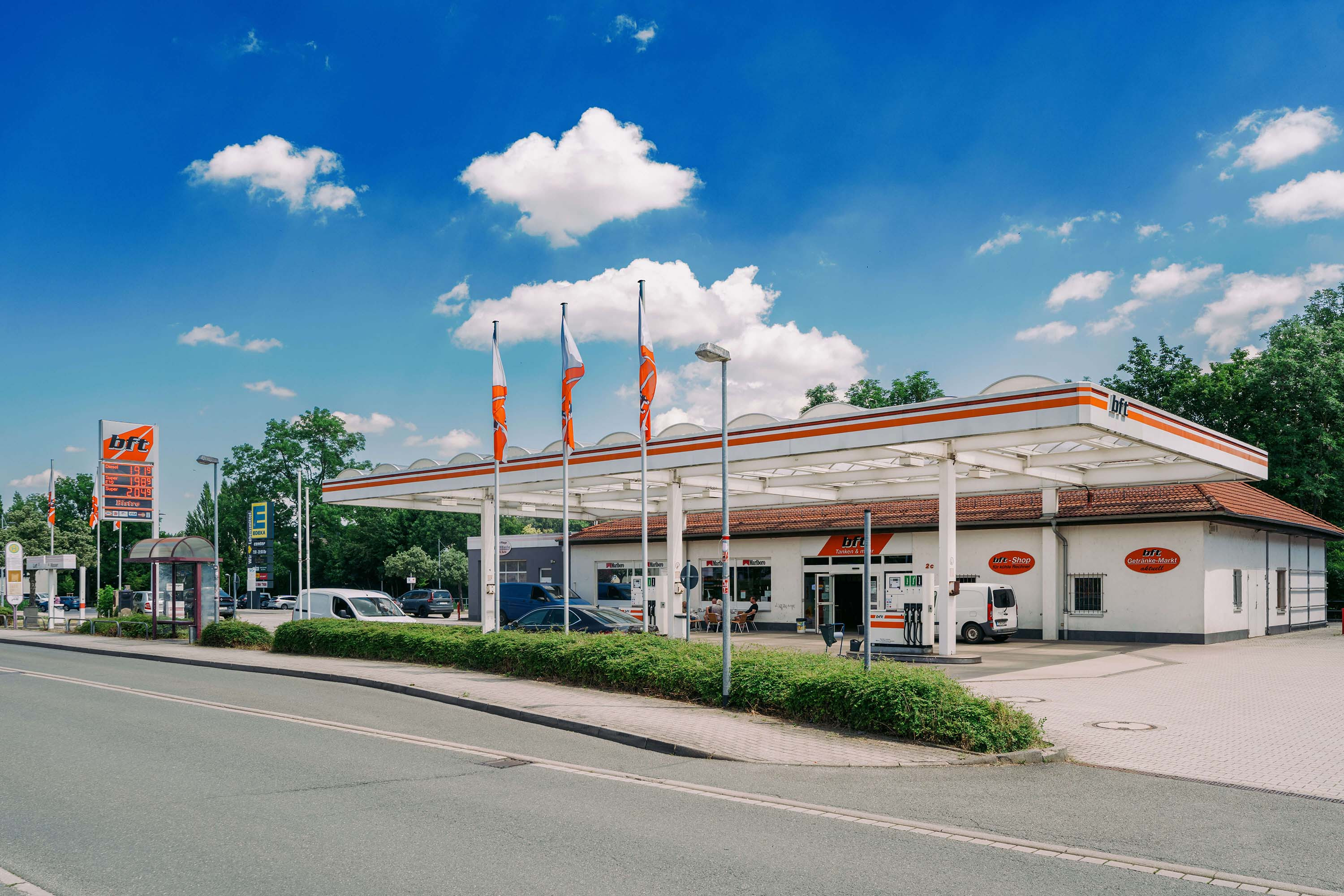 bft Tankstelle mit Shop und Zapfsäulen an einer Straße bei blauem Himmel