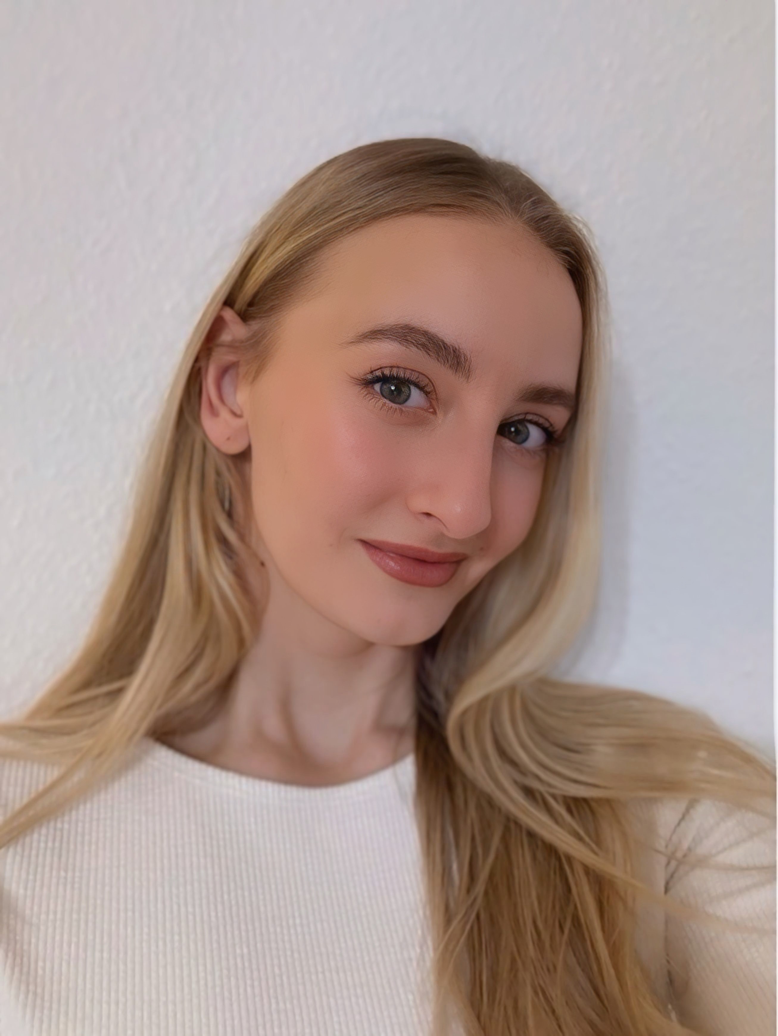 Domenica Erontschenko mit langen blonden Haaren vor weißer Wand