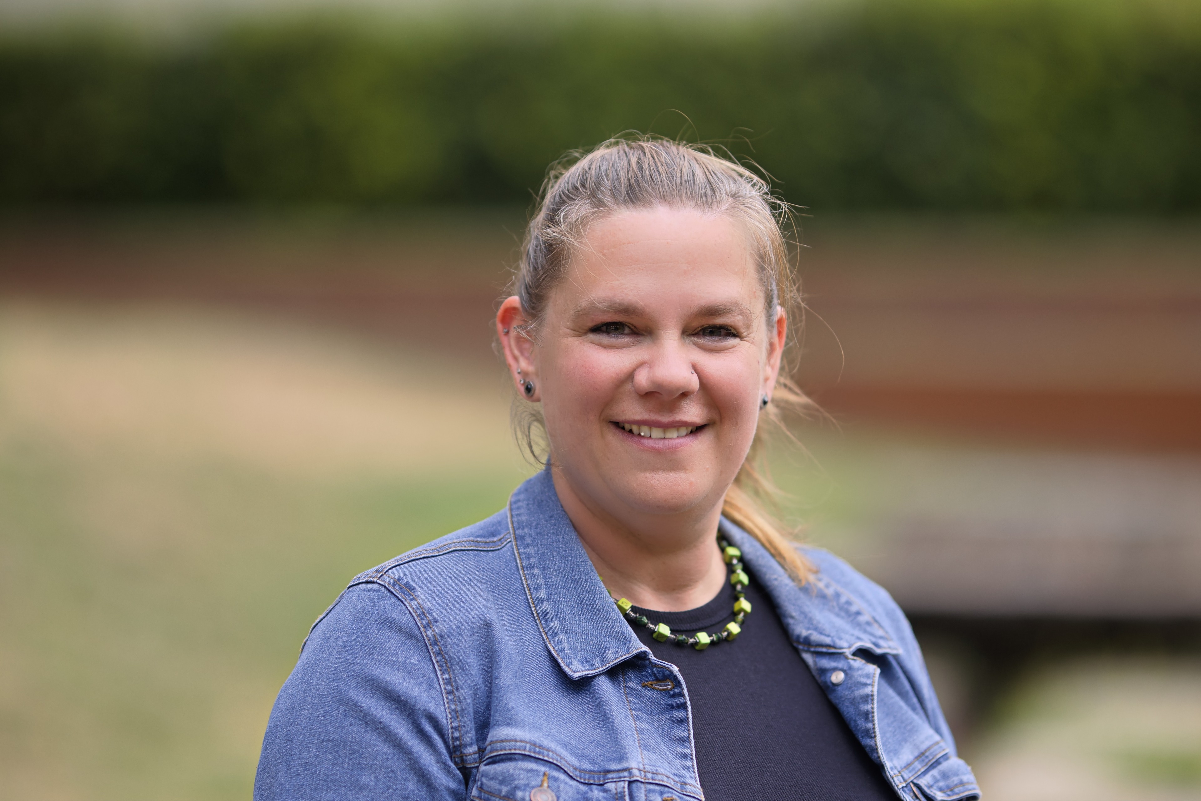Tina Munzenberger im Freien mit Jeansjacke und Halskette