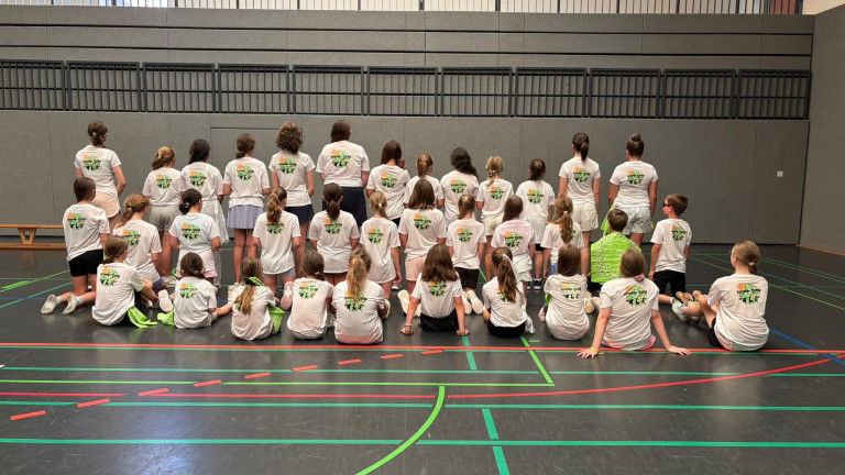 Teilnehmer des Sommercamps in der Sporthalle mit weißen T-Shirts von hinten gesehen Kindergruppe beim Sommercamp in der Sporthalle, alle mit weißen T-Shirts von hinten