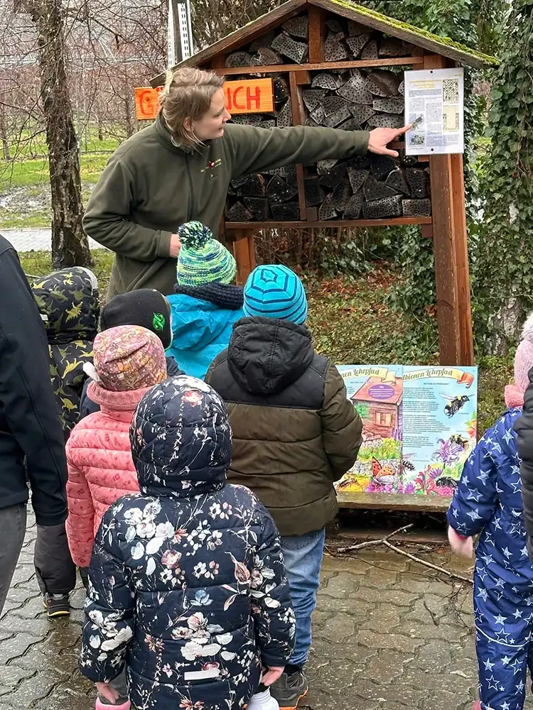 Kindergruppe bei einer Führung auf der Obstplantage Hahne vor einem Insektenhotel