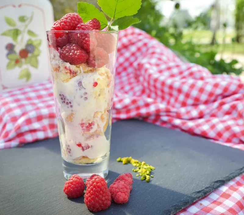 Himbeer-Zabaione Dessert mit frischen Himbeeren und Pistazien im Glas Himbeer-Zabaione Dessert im Glas mit frischen Himbeeren und Pistazien auf Schieferplatte