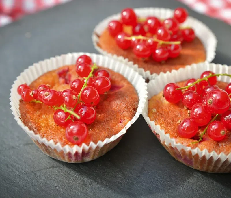 Johannisbeer-Muffins – Rezept für Muffins mit frischen roten Johannisbeeren Drei frisch gebackene Johannisbeer-Muffins mit roten Johannisbeeren als Dekoration