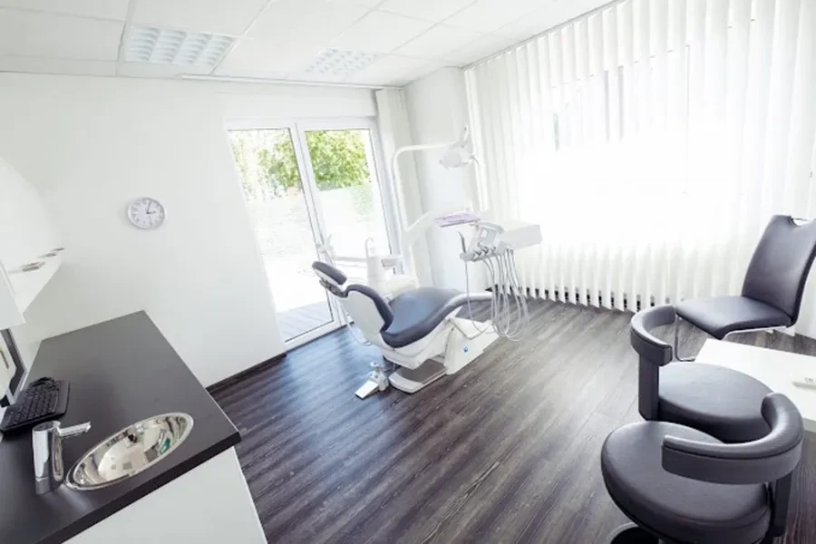 Modernes Behandlungszimmer mit Zahnarztstuhl und heller Einrichtung
