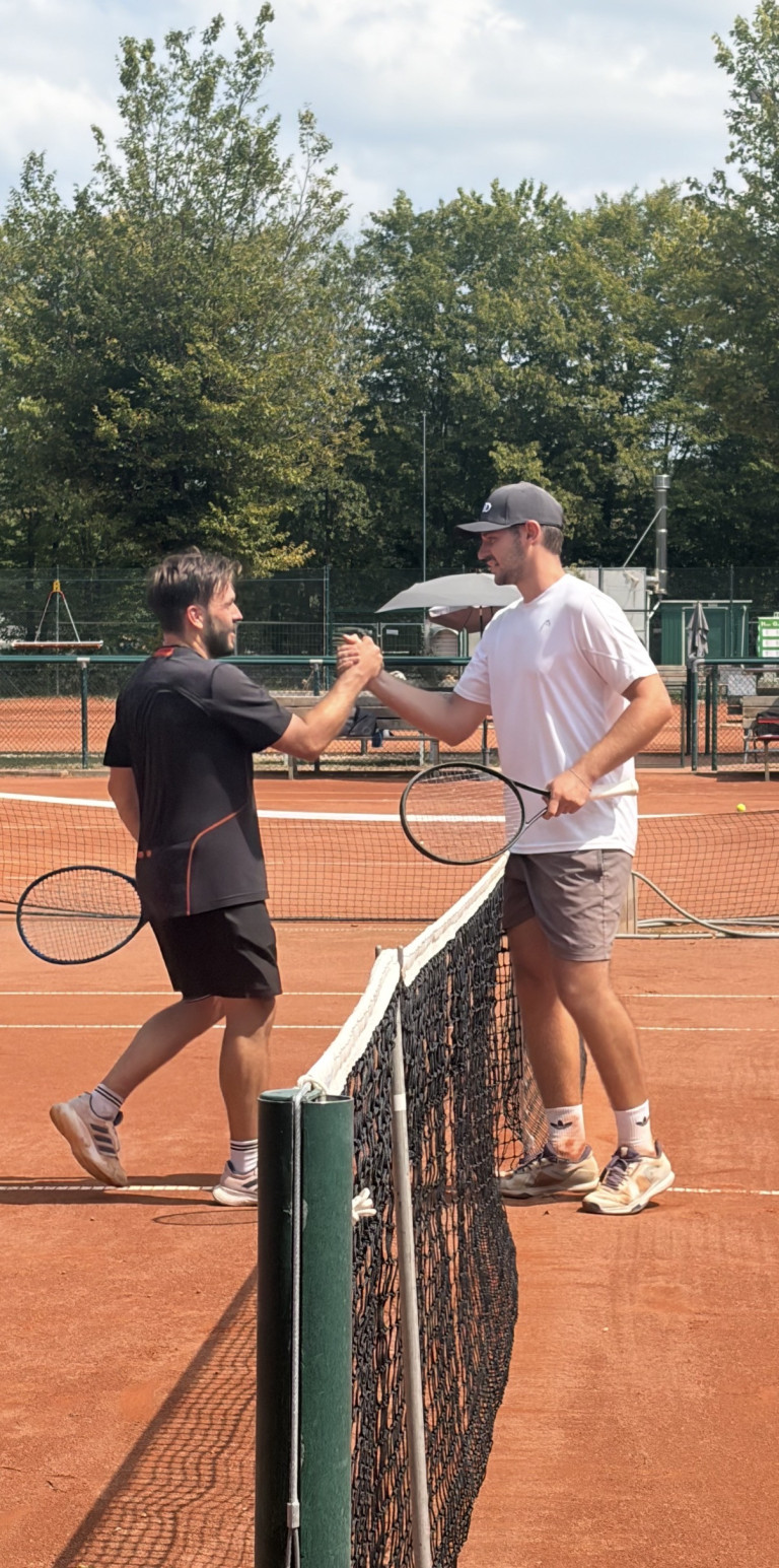 Fairplay beim Tennis: Handschlag zweier Spieler nach dem Match auf Sandplatz Zwei Tennisspieler geben sich nach einem Match auf einem Sandplatz die Hand am Netz