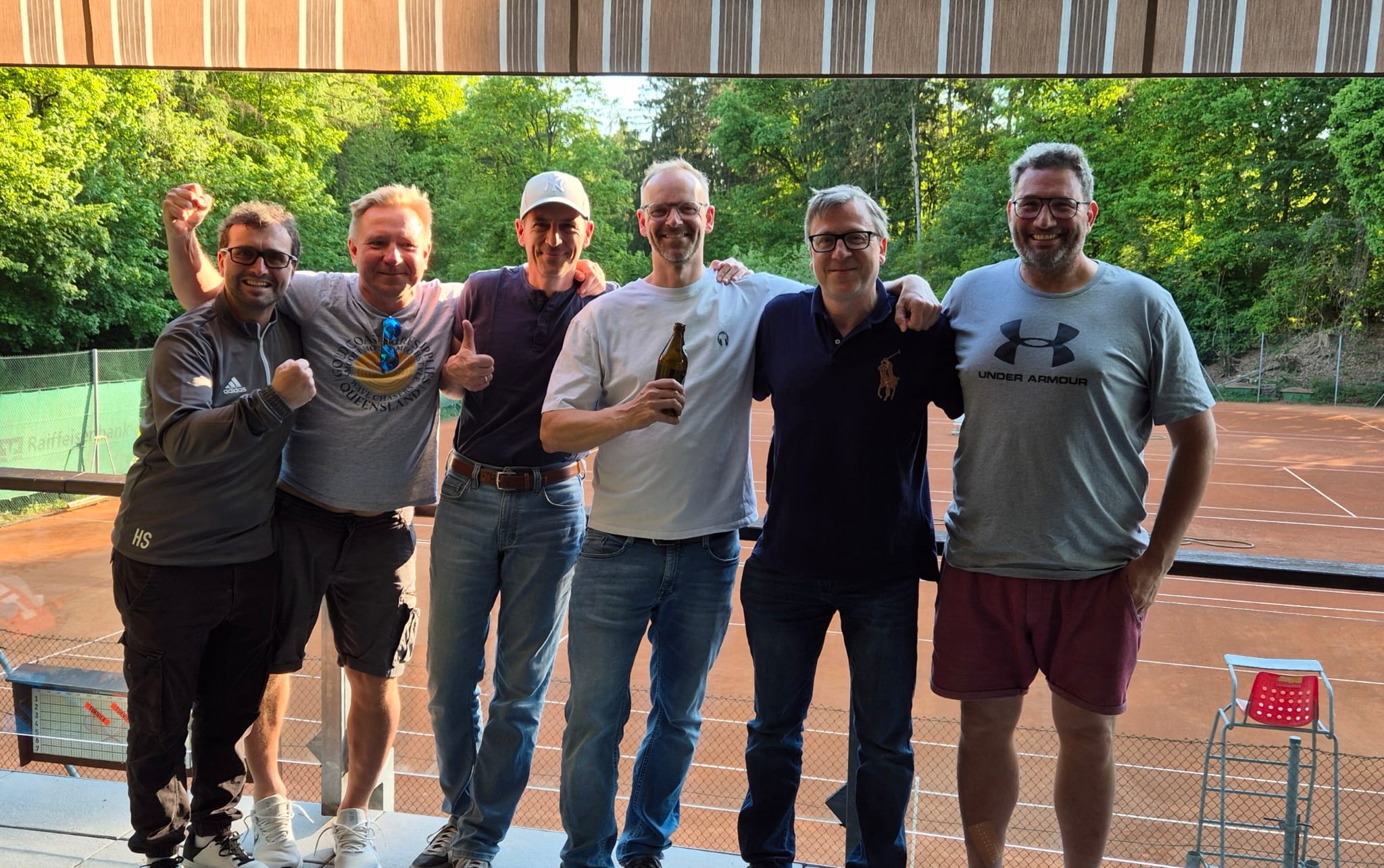 Gruppe von Männern auf einem Tennisplatz im Freien, sommerliche Stimmung