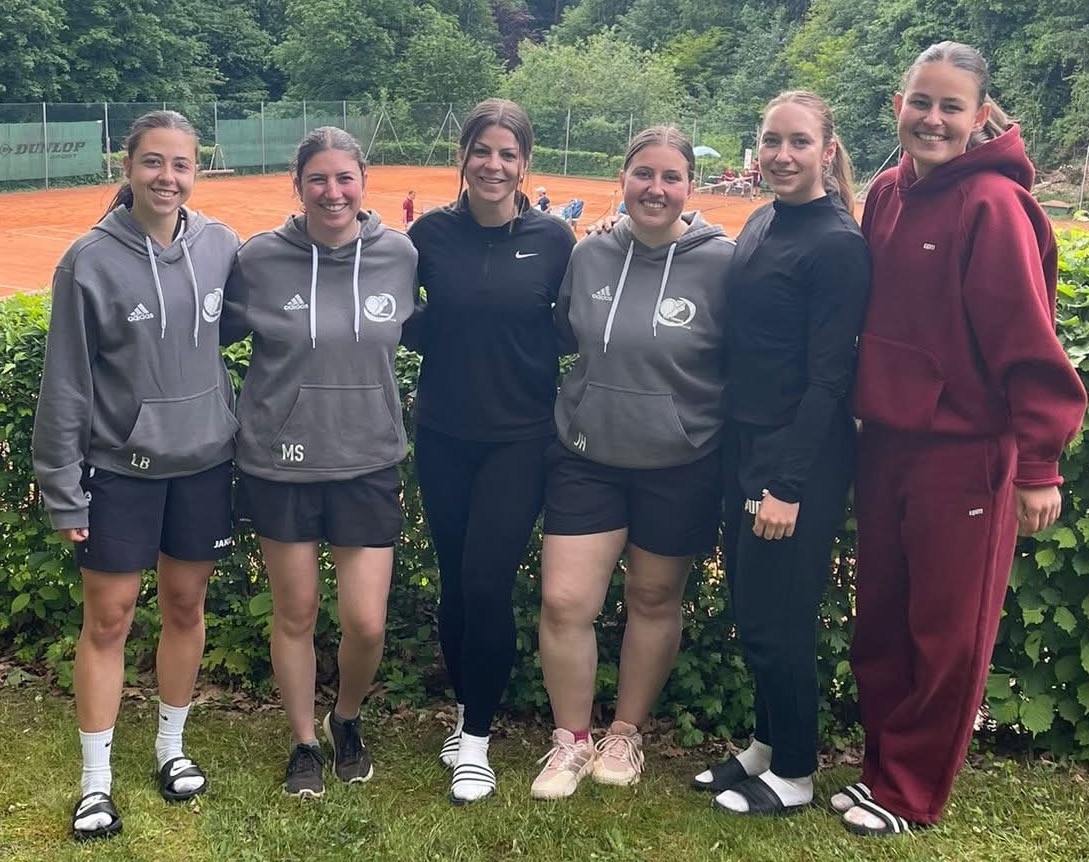 Gruppenfoto eines Damen-Tennisteams vor einem Tennisplatz im Freien