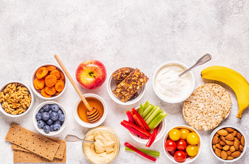 Auswahl an gesunden Snacks mit Obst, Müsli und Gemüse auf hellem Hintergrund