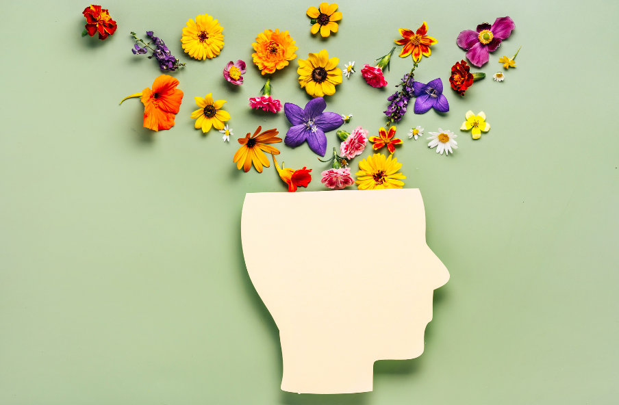 Silhouette eines Kopfes mit bunten Blumen auf grünem Hintergrund
