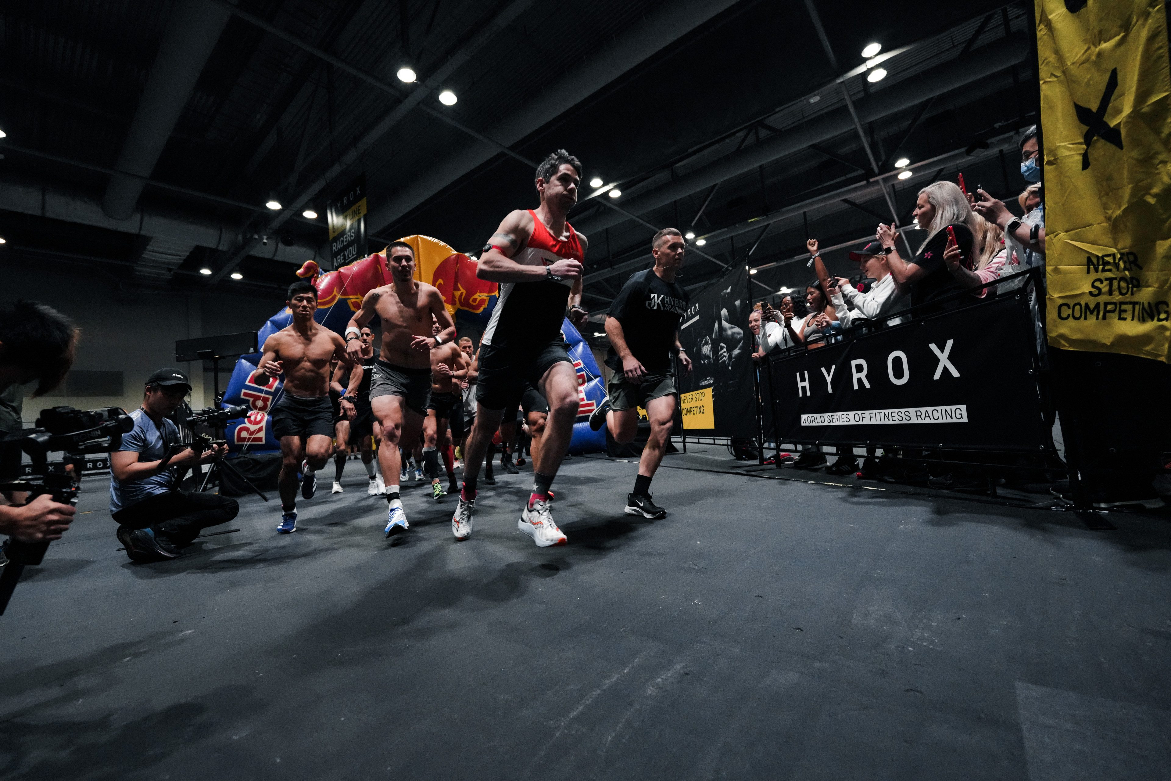 Teilnehmer starten beim HYROX Fitnessrennen, Indoor-Event mit Red Bull Startbogen