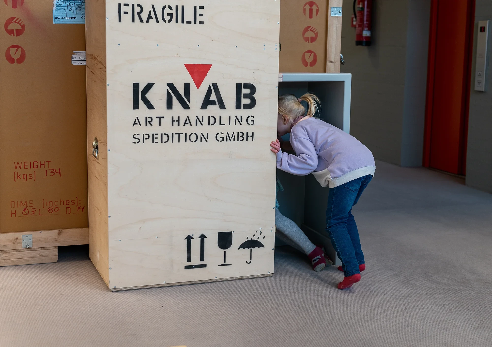 Kind spielt an einer Transportkiste von KNAB Art Handling Spedition GmbH – Beitrag zum Thema Mimese