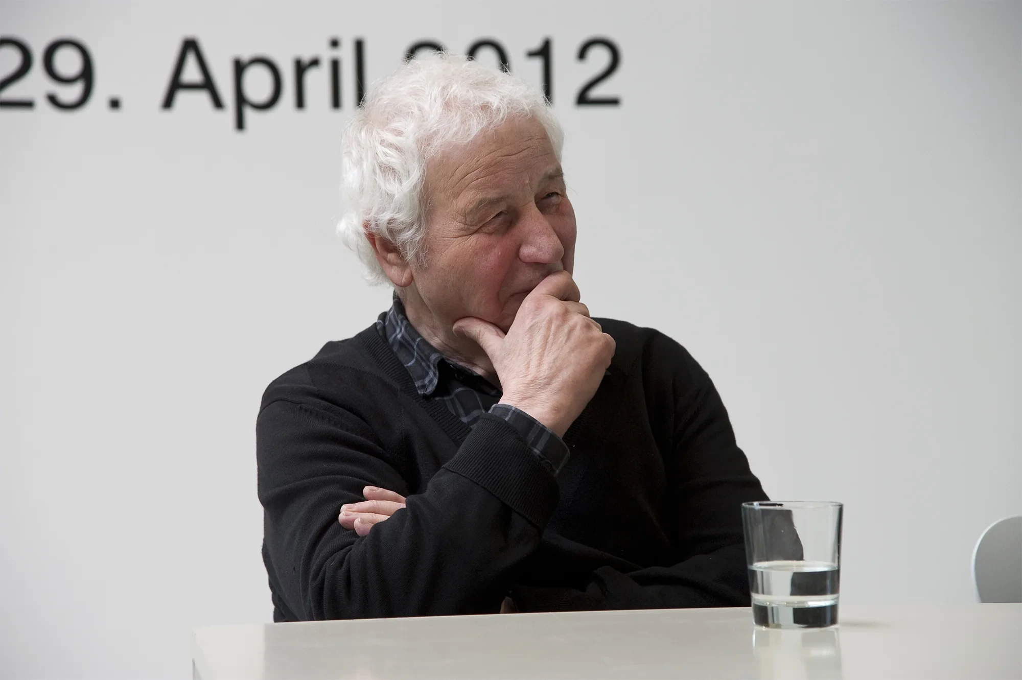 Ilya Kabakov bei einer Veranstaltung im April 2012, nachdenklich am Tisch mit einem Glas Wasser