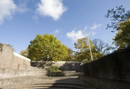 Blick auf den Skulpturengarten mit moderner Skulptur und Bäumen unter blauem Himmel