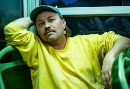 Porträt von Joar Nango in gelbem Pullover und grüner Kappe, Beitrag über Joar Nango