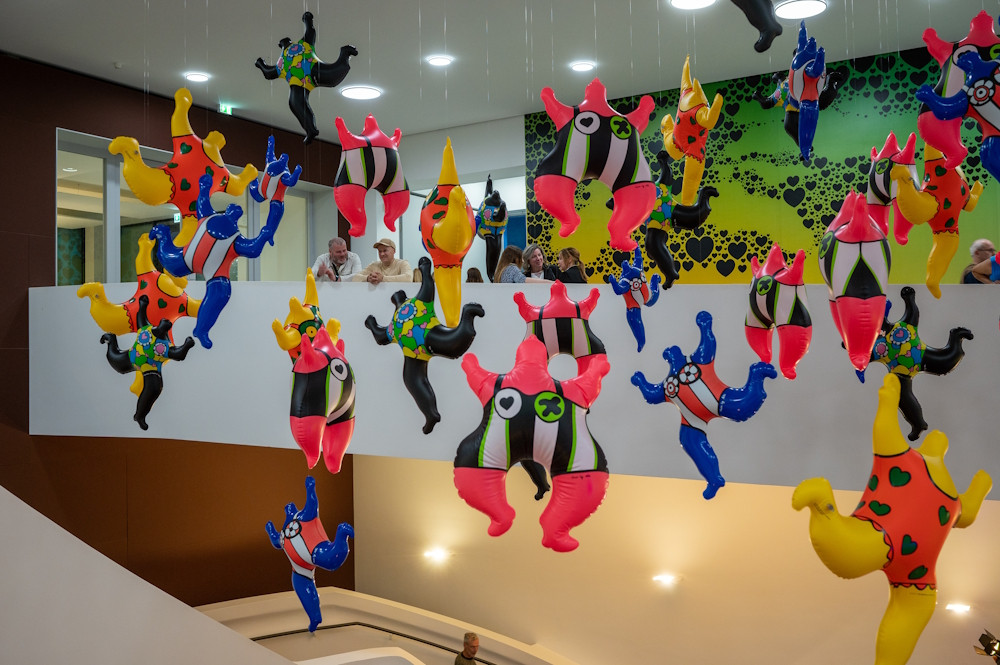 Bunte aufblasbare Figuren als Kunstinstallation in einem modernen Gebäude, Menschen betrachten die Ausstellung