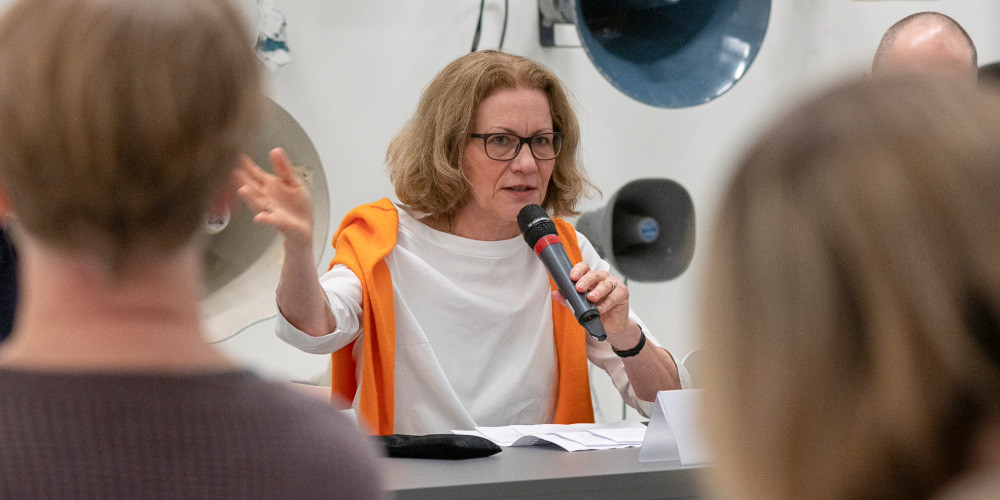 Isabel Schulz hält einen Vortrag und spricht mit Mikrofon vor Publikum