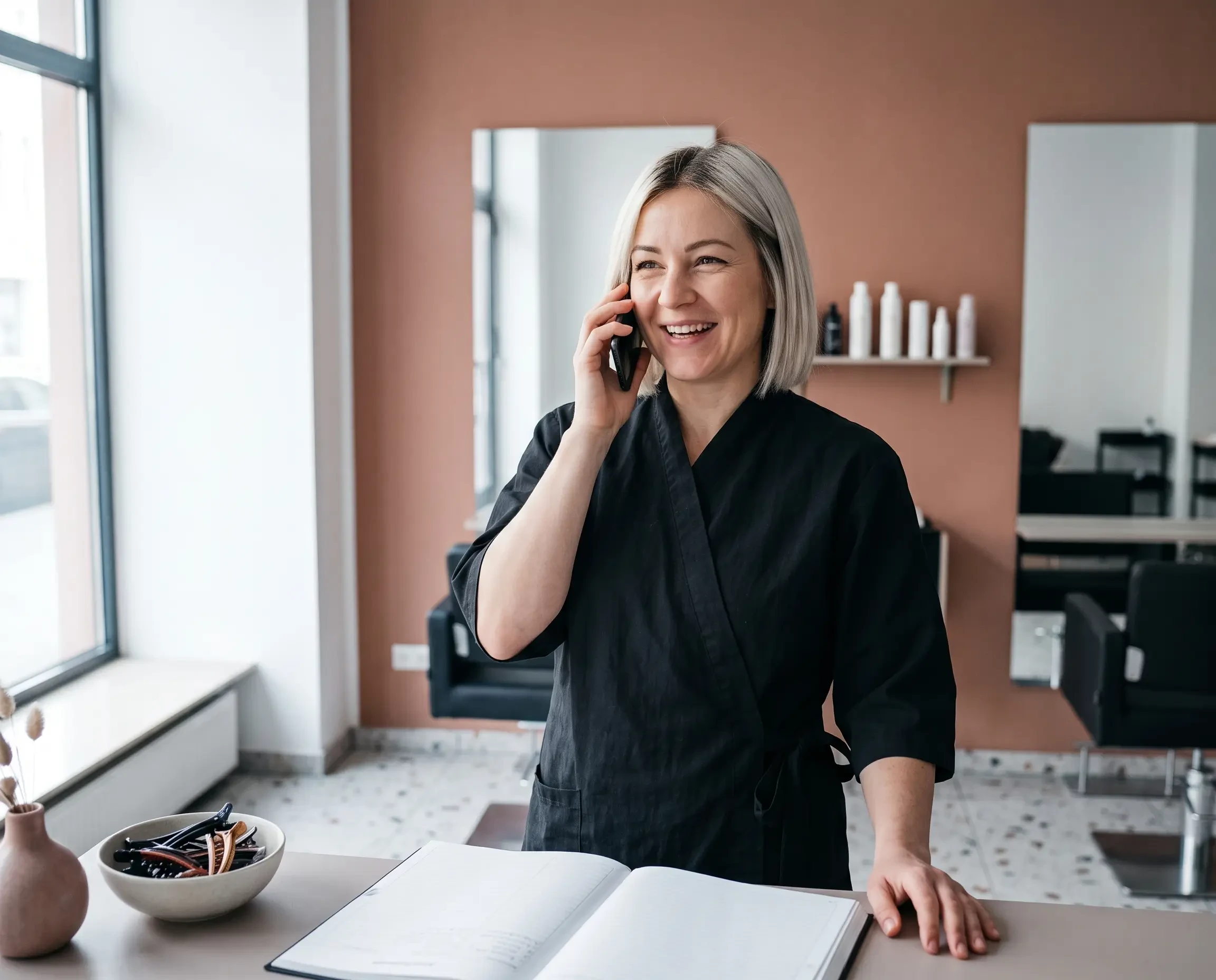Friseurin im Salon telefoniert und plant Termine – modernes Friseurgeschäft (KI-generiert)
