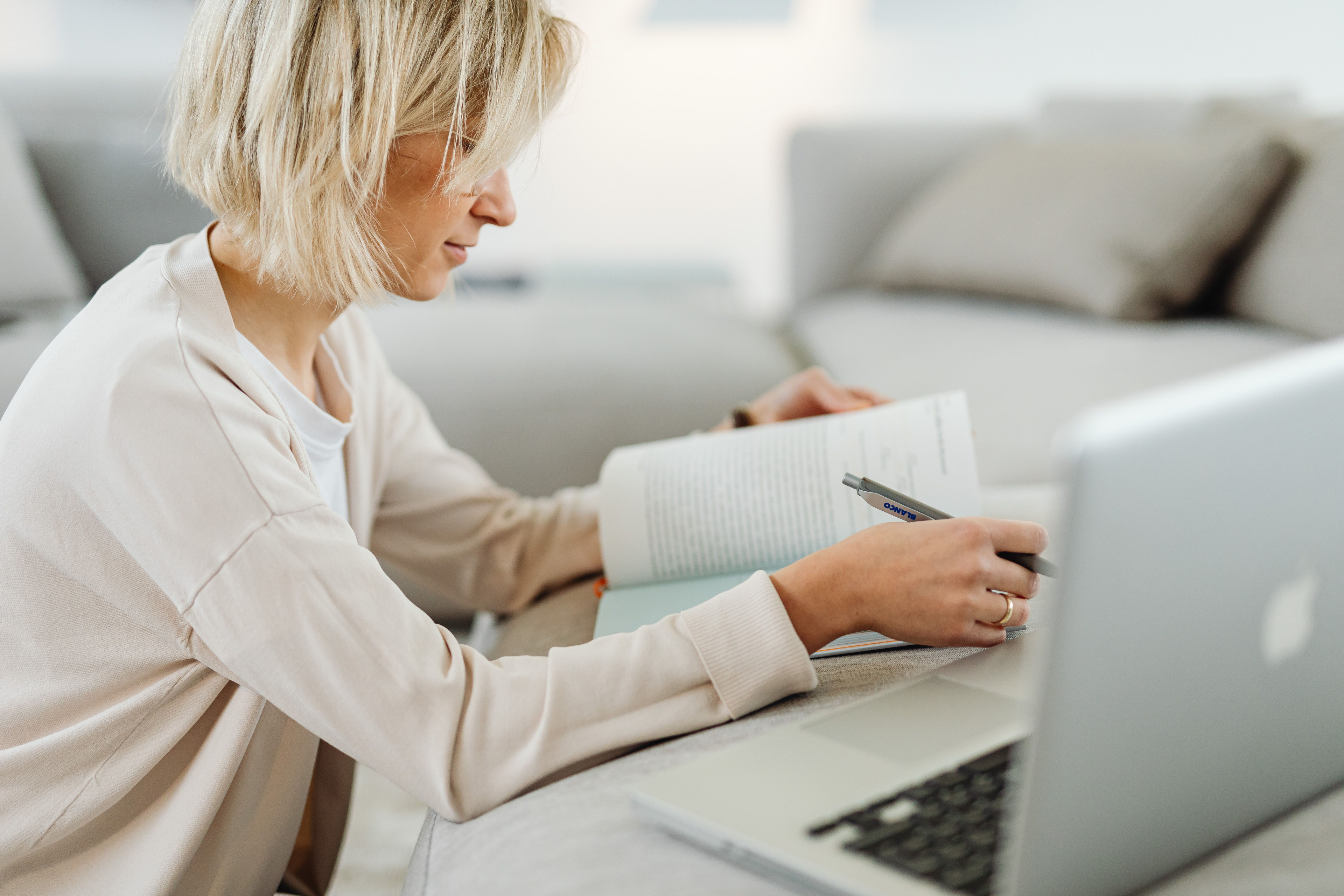 Person arbeitet mit Laptop und Stift an einem Buch