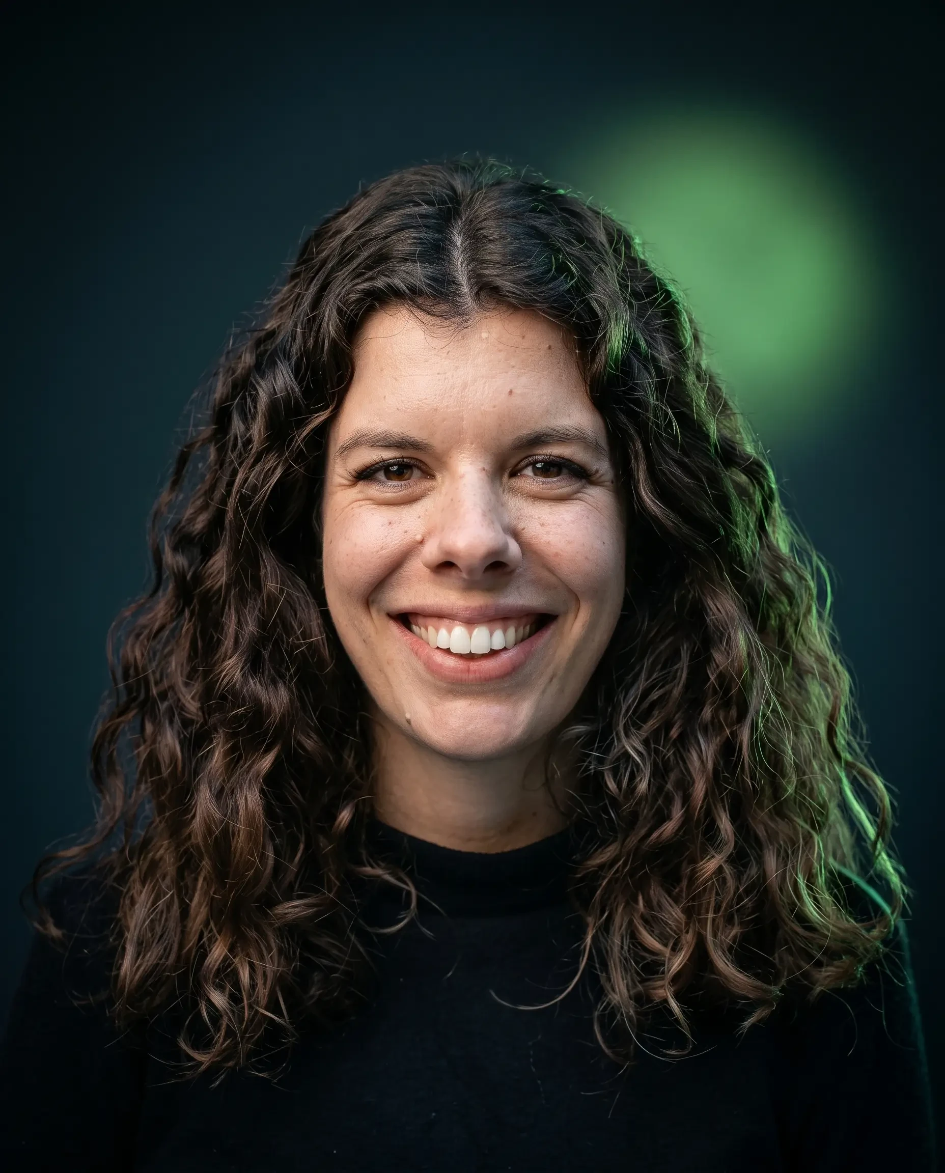 Porträt einer lächelnden Frau mit lockigen Haaren vor dunklem Hintergrund, gemini-generated-image-i8qfjbi8qfjbi8qf