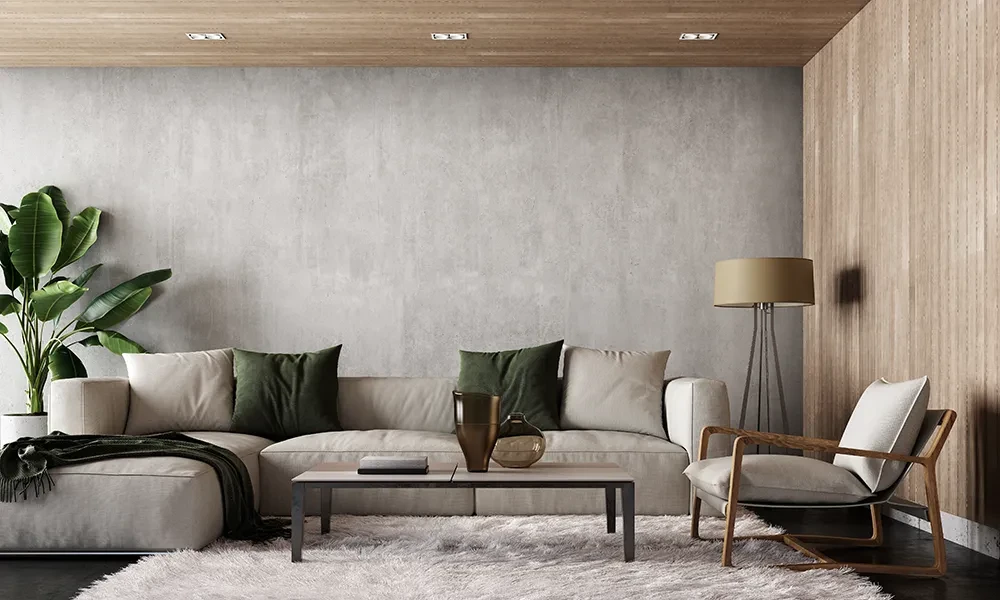 Modernes Wohnzimmer mit beiger Couch, grünen Kissen, Holztisch und Stehlampe vor Betonwand