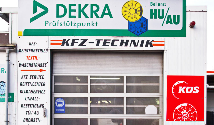 DEKRA KÜS Prüfstützpunkt für KFZ-Technik mit HU/AU Plaketten