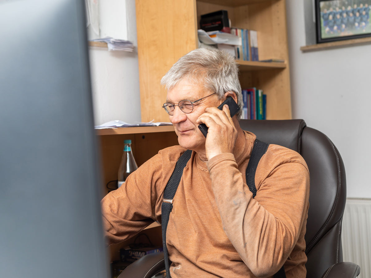 Herr Behrens telefoniert im Büro am Schreibtisch