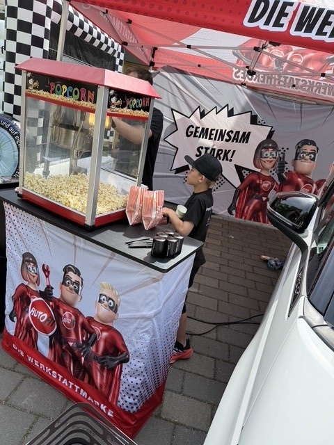 Popcornstand bei Koppel und Gerum Event mit Kind und Comic-Figuren, Banner mit Slogan 'Gemeinsam stark!'