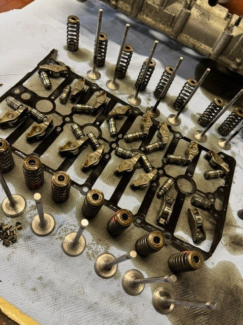Zerlegte Motorteile wie Ventile, Ventilfedern und Kipphebel auf einer Werkbank