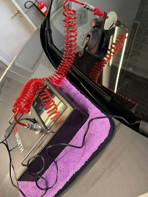 Würth Gerät mit rotem Spiralkabel auf violettem Tuch bei der Fahrzeugwartung