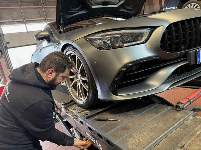 Mechaniker bei der Wartung eines Mercedes auf einer Hebebühne in der Werkstatt