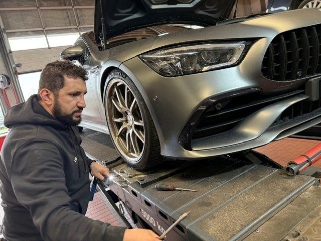 Mechaniker bei der Wartung eines modernen Autos auf einer Hebebühne in der Werkstatt