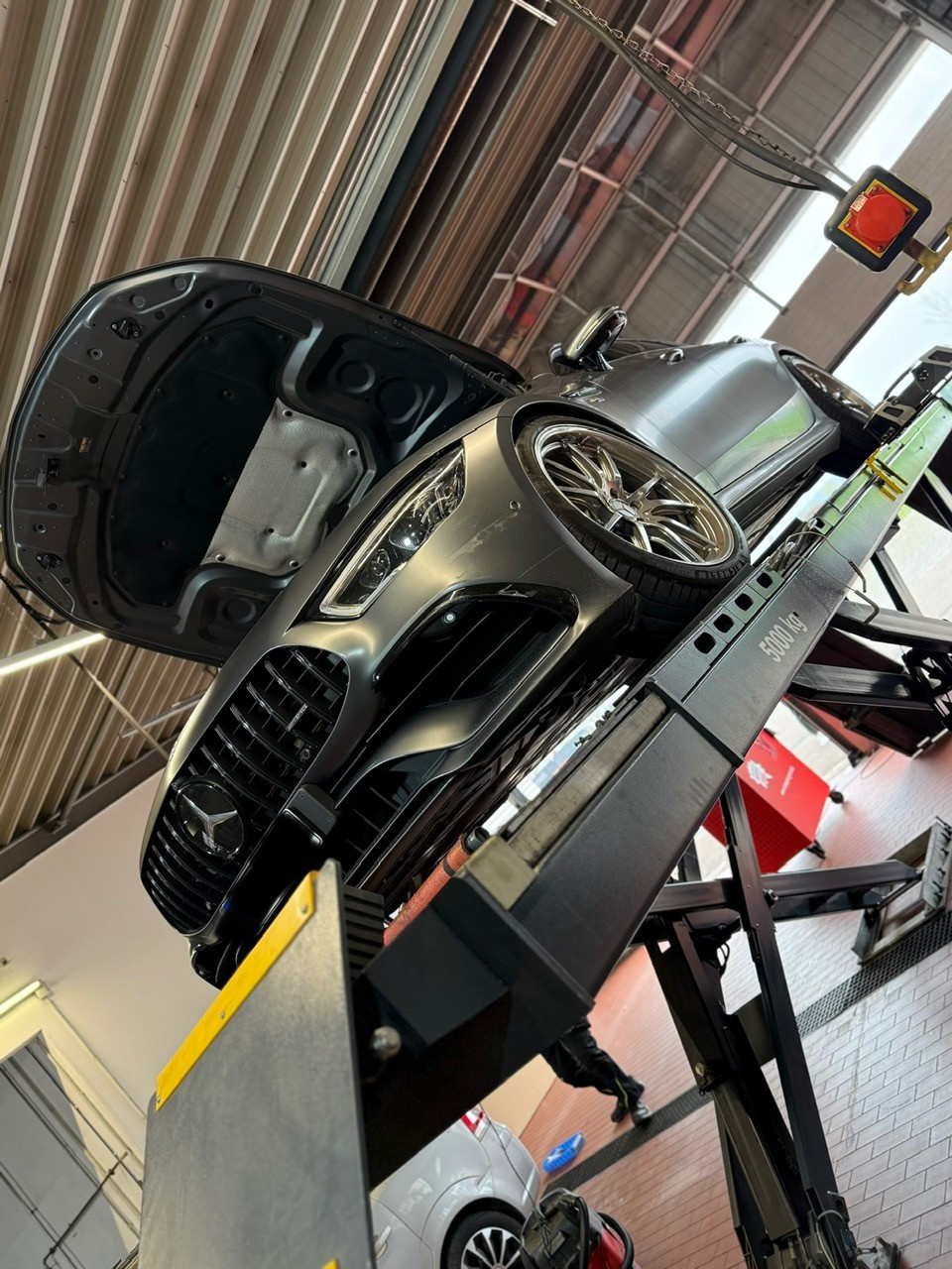 Auto auf Hebebühne mit geöffnetem Motorraum in einer Werkstatt