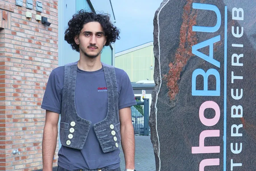 Person vor einem Bauunternehmen Person vor einem Bauunternehmen mit Schild