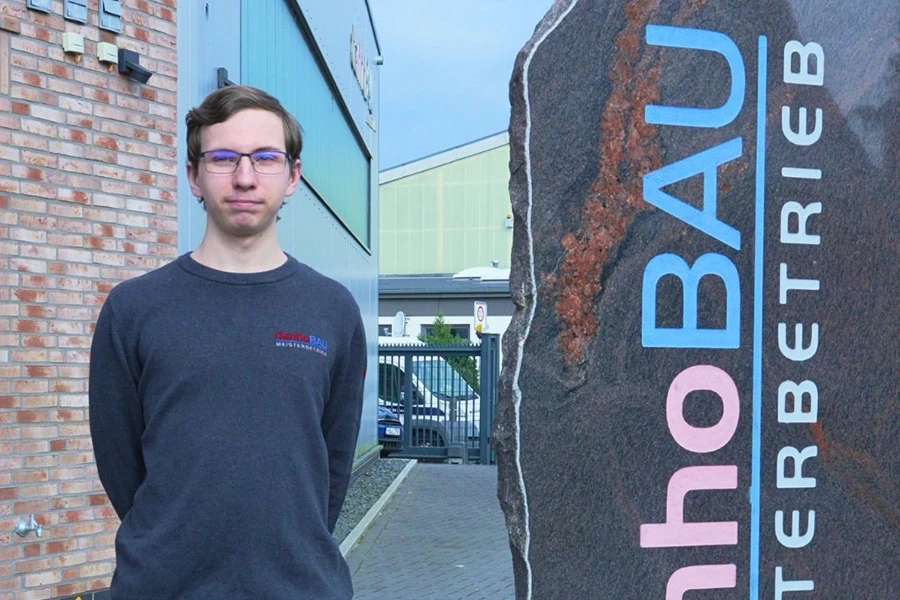 Benjamin B. - Azubi vor Firmengebäude Benjamin B. als Azubi vor einem Firmengebäude