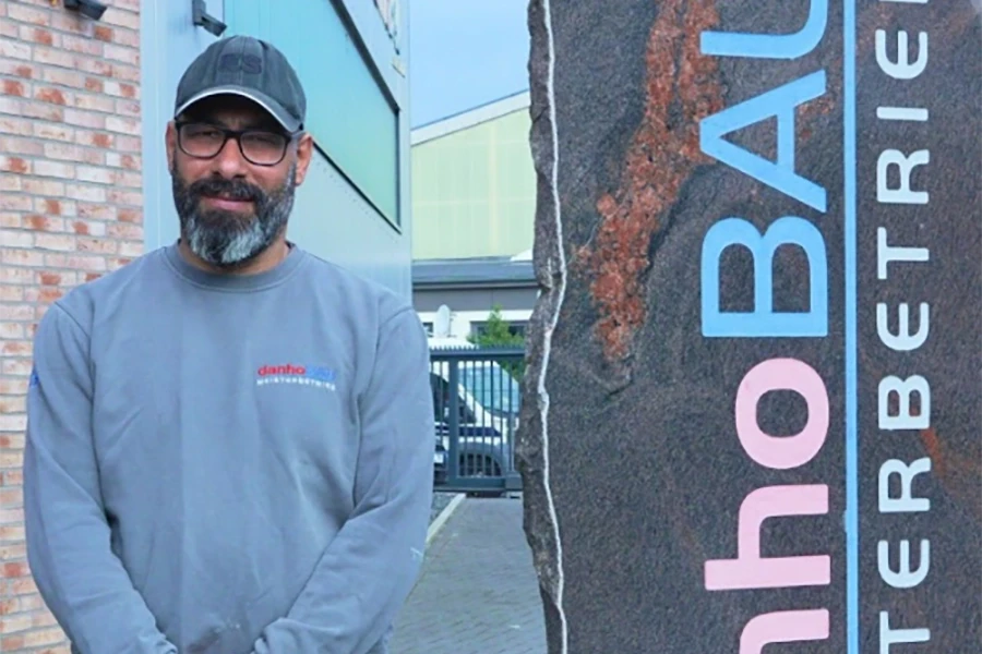 Person vor einem Gebäude mit Schild 'danhoBAU' Person vor einem Gebäude mit Schild 'danhoBAU'