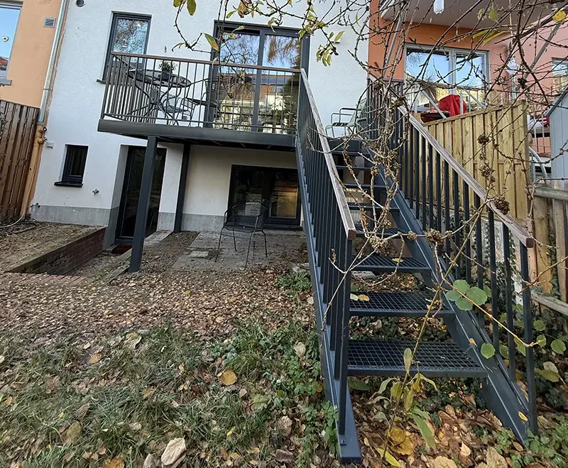Moderne Metall-Außentreppe mit Balkon an einem Einfamilienhaus im Herbst