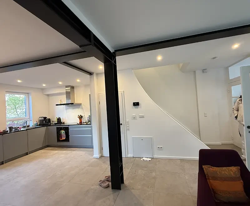 Moderne offene Küche und Wohnbereich mit sichtbaren Stahlträgern und Treppe