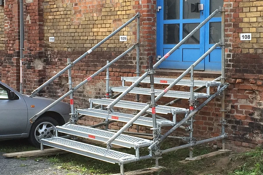 Fluchttreppe aus Metall vor einem Backsteingebäude mit blauer Tür