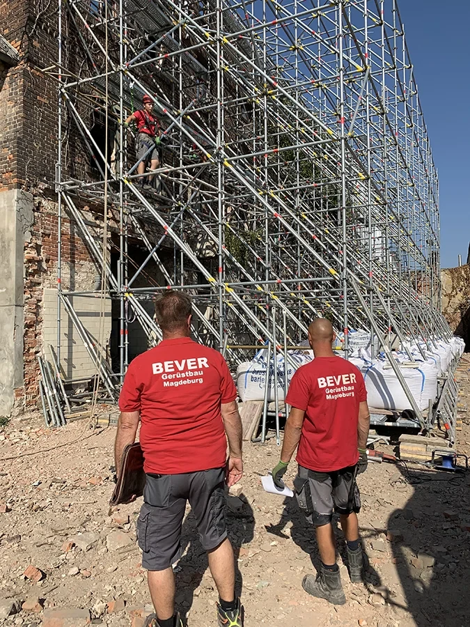 Mitarbeiter von BEVER Gerüstbau Magdeburg auf einer Baustelle vor einem großen Baugerüst