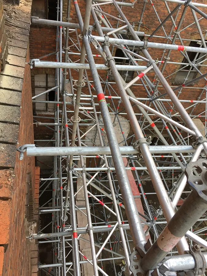 Statisches Gerüst aus Metallrohren an einer Backsteinfassade für Bauarbeiten