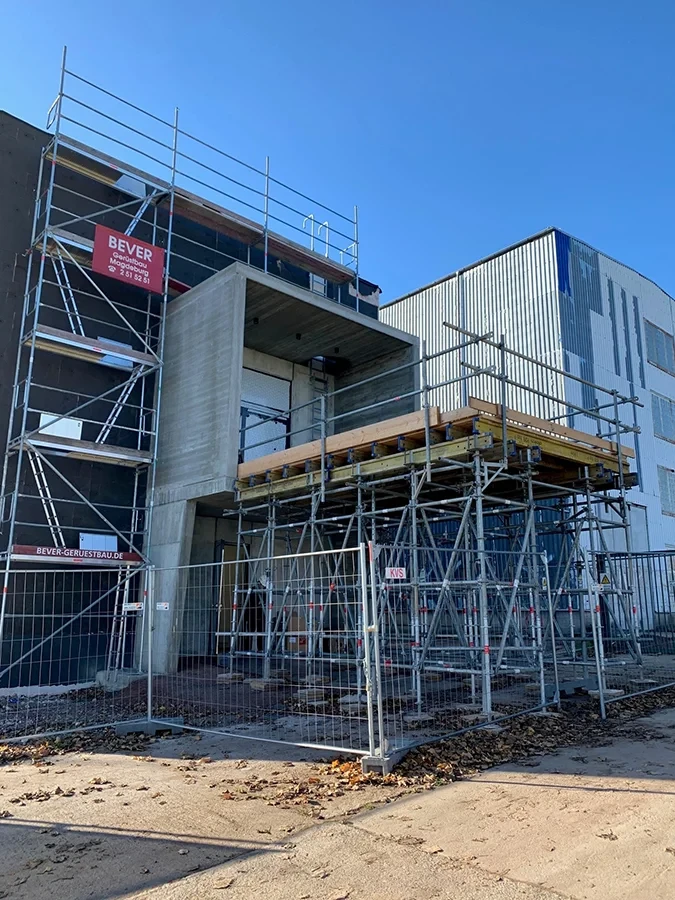 Traggerüst und Baugerüst an einer modernen Baustelle bei sonnigem Wetter