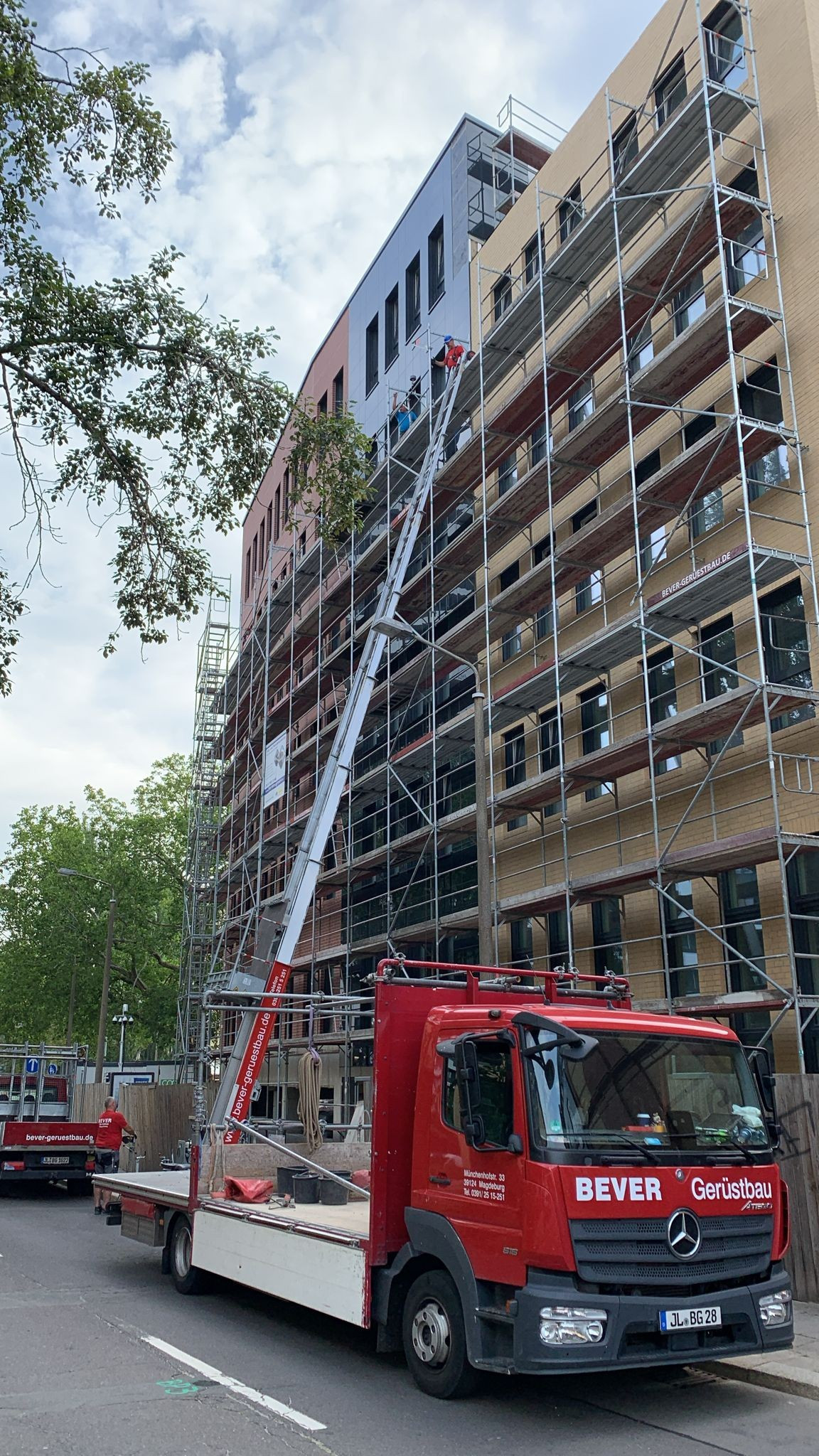 Bauaufzug an Gerüst vor einem mehrstöckigen Gebäude auf einer Baustelle