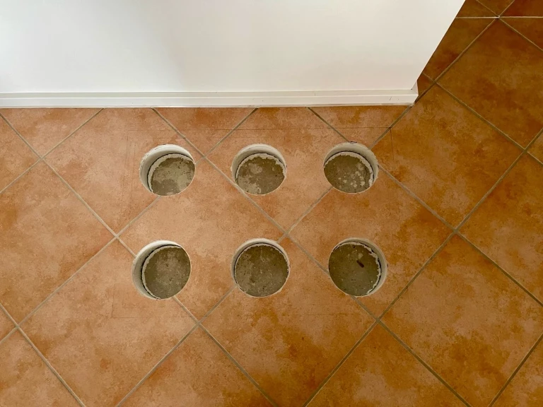 Sechs Bohrlöcher im Fliesenboden am 25.02.2026 Sechs kreisrunde Bohrlöcher in Fliesenboden, aufgenommen am 25.02.2026