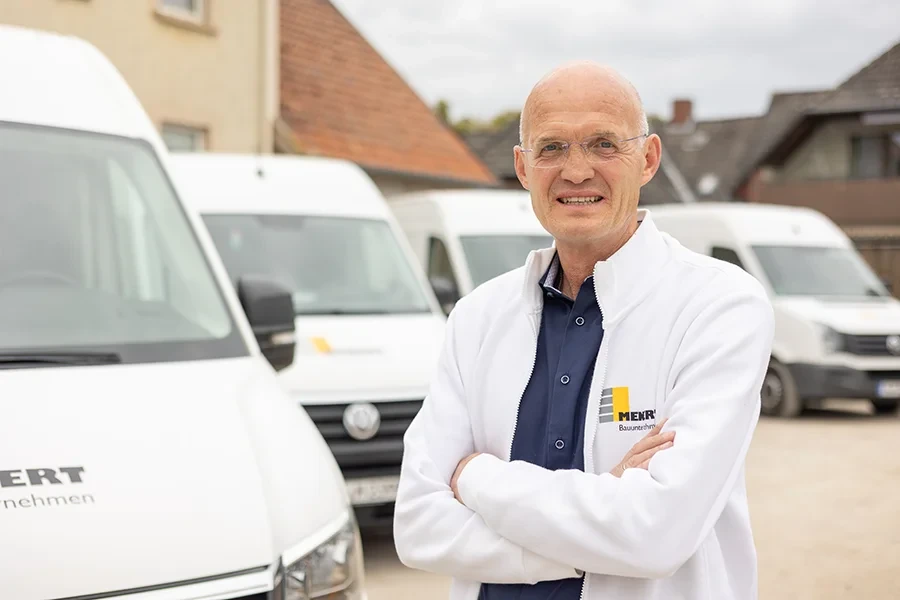 Dirk Kruse vor Firmenfahrzeugen der MERK Bauunternehmung