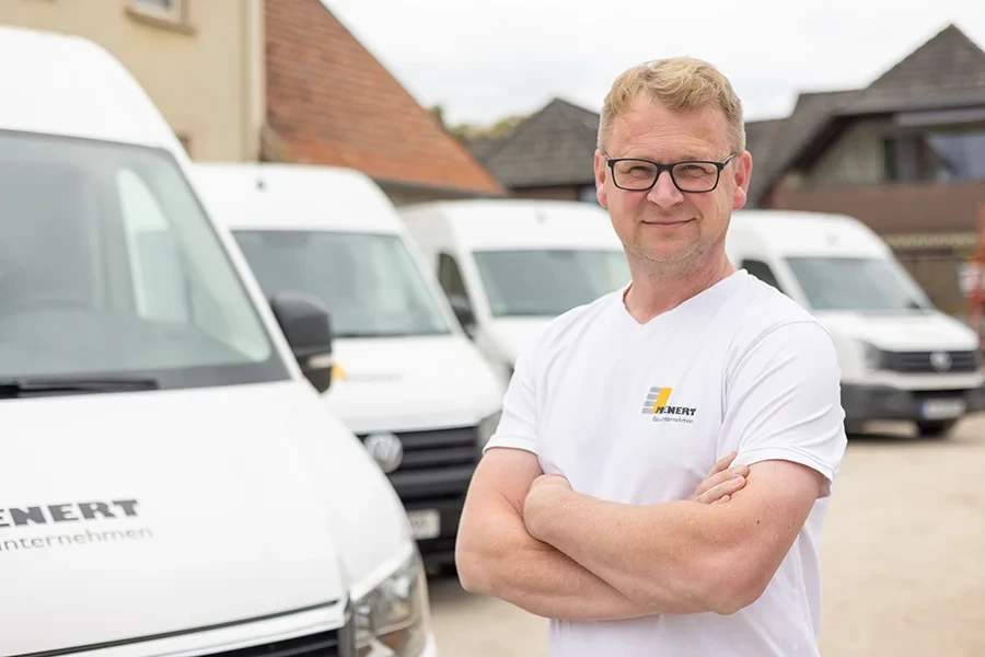 Rene Huyer, Maurermeister, vor Firmenfahrzeugen auf dem Betriebsgelände