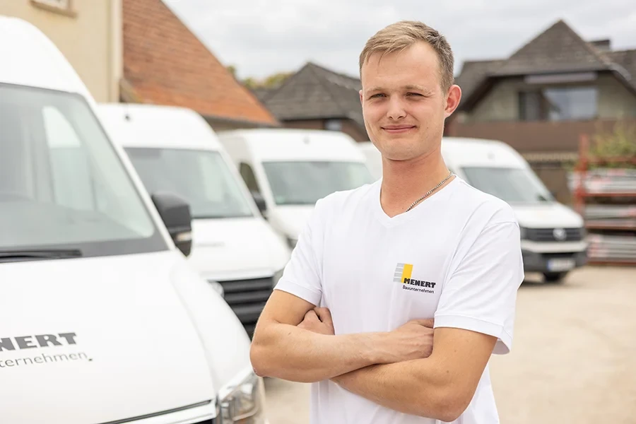 Darius Kruse vom Bauunternehmen Menert vor weißen Transportern