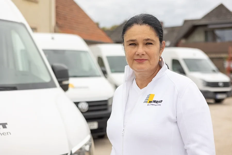 Donata Kruse vom Bauunternehmen Menert vor Firmenfahrzeugen