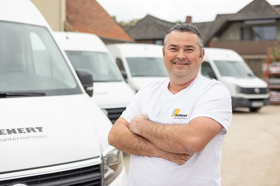 Mariusz Mirowski vom Bauunternehmen Hebert steht vor mehreren weißen Transportern