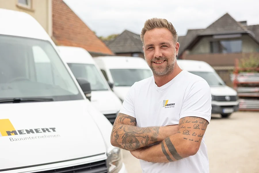 Müller Philop vor Firmenfahrzeugen mit Tätowierungen und T-Shirt der Marke Zenert