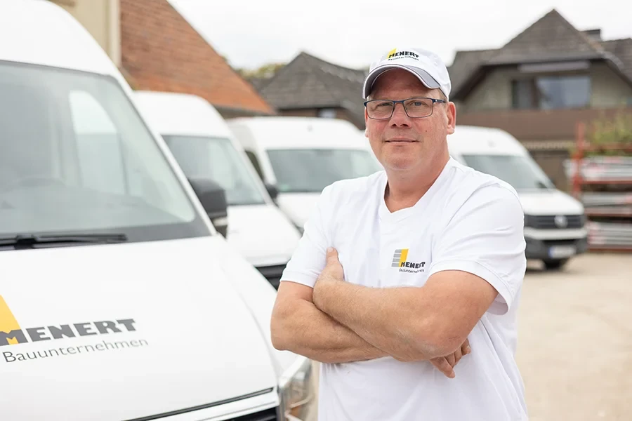 Björn Müller vor Firmenfahrzeugen von HENERT im Arbeitsoutfit
